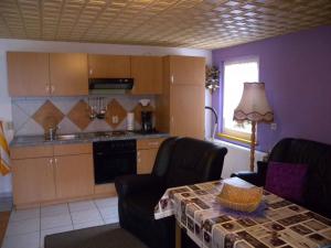 eine Küche mit einem Tisch und Stühlen sowie eine Küche mit lila Wänden in der Unterkunft Apartment Kamminke 2 in Kamminke