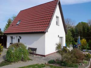 a white house with a red roof and a bench at Holiday home in Klein Kedingshagen 2755 in Klein Kedingshagen