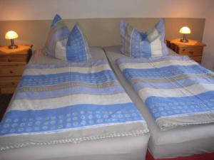 two beds with blue and white sheets and pillows at Holiday home Groß Kordshagen/Ostsee 2741 in Arbshagen