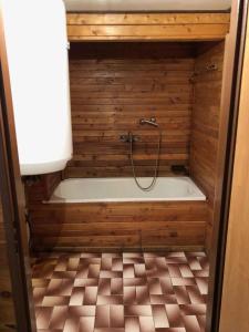 eine Badewanne mit einer Dusche an einer Holzwand in der Unterkunft Holiday home Strazne/Riesengebirge 2326 in Strážné