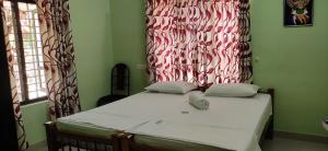 1 dormitorio con 1 cama con cortina roja y blanca en SEVENSTAR RESIDENCY en Varkala