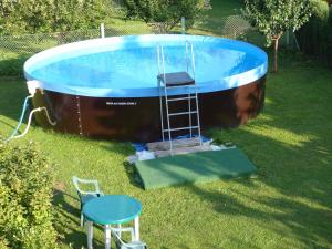 basen z drabiną obok stołu i stołka w obiekcie Holiday home Vrchlabi/Riesengebirge 2190 w mieście Podhŭří