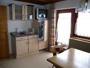 uma cozinha com armários de madeira e uma televisão na parede em Apartments in Bruck am Ziller/Zillertal 857 em Großhartberg