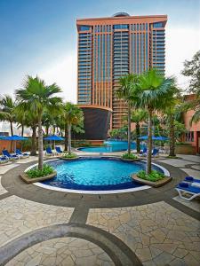 a resort pool with palm trees and a tall building at Grand Service Apartment @ Times Square in Kuala Lumpur