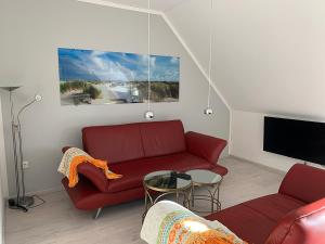 a living room with a red couch and a tv at Dünentraum, Ferienwohnung für 4 Personen - Erwachsene oder Kinder - in DE FEERJENHUSEN am Haubarg von Vollerwiek, Fertigstellung April 2020 in Vollerwiek