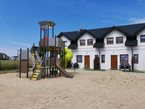 a playground in the sand in front of a house at Domki LUNA in Sarbinowo +6 photos