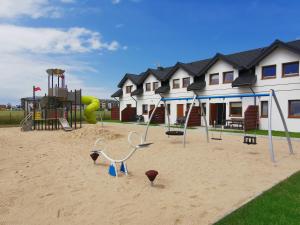 a playground in the sand in front of a house at Domki LUNA in Sarbinowo