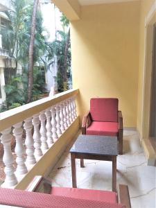 una sedia rossa seduta su un balcone con finestra di Casa Joseph a Candolim