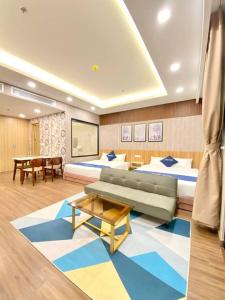 Cette chambre comprend deux lits, un canapé et une table. dans l'établissement FLC SEA TOWER Quy Nhon- Kizz House, à Quy Nhơn