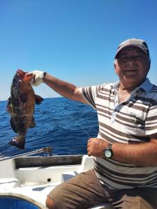 a man is holding a fish in the air at Emmanouil in Kythira