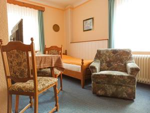 a bedroom with a bed and a chair and a chair at Landhotel Waldschänke in Berlin