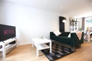 a living room with a green couch and a tv at Stylish Cambridge City Pad in Chesterton