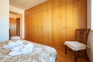 a bedroom with a bed with a chair and wooden cabinets at Lighthouse View in Cascais in Cascais +28 photos