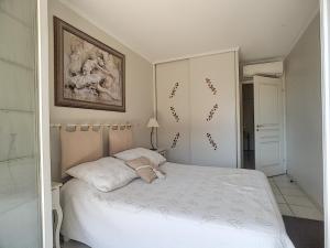 Un dormitorio con una cama blanca y una pintura en la pared en ZEN MARINA en Mandelieu-la-Napoule