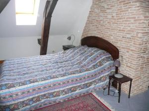 a bedroom with a bed with a brick wall at gite la chapelle in Nailhac +3 photos