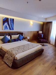 贾姆讷格尔The Fern Residency, Jamnagar的带一张大床和一把椅子的卧室 更多25张照片