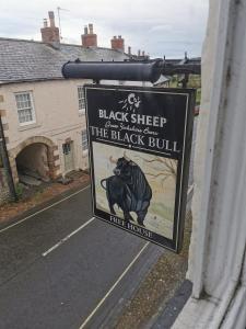 a sign on the side of a house with a black sheep and the black bull at The Black Bull Inn in Middleham
