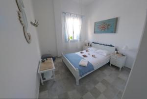 a small white bedroom with a bed and a window at Symi . VILLA CALME (Sur la Mer). in Symi