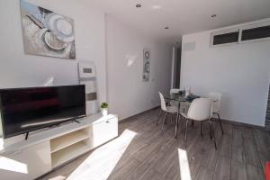 - un salon avec une télévision, une table et des chaises dans l'établissement Los Molinos apartment Ocean View, à Playa del Ingles