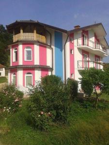 un edificio de color rosa y blanco con balcón en Vila Anđelija en Velika Kladuša