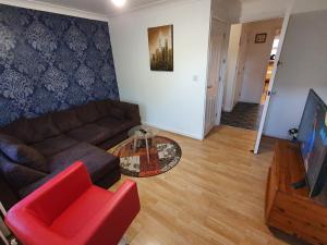 a living room with a couch and a red chair at Mannys Apartment - Nice & Cozy 4Bed Flagship Lodge in Sittingbourne