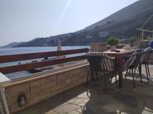 einen Tisch und Stühle auf einem Balkon mit Blick auf das Wasser in der Unterkunft Symi . VILLA CALME (Sur la Mer). in Symi