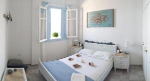 a white bedroom with a bed with shoes on it at Symi . VILLA CALME (Sur la Mer). in Symi