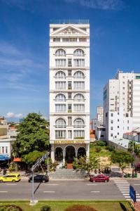 a tall white building in a city with a parking lot at Sea Phoenix Hotel Da Nang in Danang +189 photos