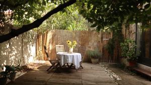 La Summer House avec Jardin في آرل: طاولة مع كراسي و مزهرية من الزهور على الفناء