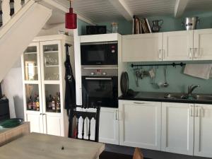 eine Küche mit weißen Schränken und einer Mikrowelle in der Unterkunft A Room with a View - Maisonnette dans bourg médiéval au bord du Lac Léman in Yvoire