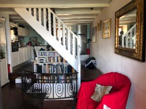 a living room with a red couch and a book shelf with books at A Room with a View - Maisonnette dans bourg médiéval au bord du Lac Léman in Yvoire