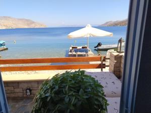 a view of the ocean from a bench with an umbrella at Symi . VILLA CALME (Sur la Mer). in Symi