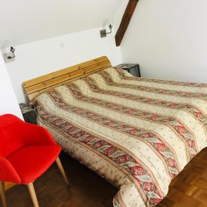 Ce lit se trouve dans un dortoir doté d'une chaise rouge. dans l'établissement gite Le Verdier, à Nailhac