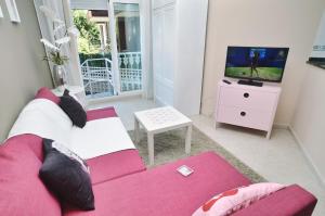 a living room with a pink couch and a tv at La Barrosa in Isla