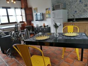 a dining room with a table and yellow chairs at Apartamentos rurales Balcón del Marqués in Cangas de Onís
