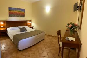 una camera d'albergo con letto e tavolo con fiori di Hotel Ristorante Le Querciolaie dei Ricci a Fonteblanda