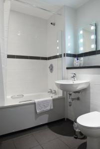 a bathroom with a sink and a tub and a toilet at The Barns Hotel in Cannock