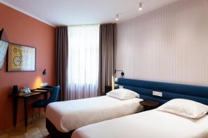 a hotel room with two beds and a desk at Hotel Perrin - former Carlton in Luxembourg