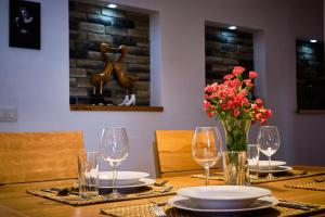 a table with glasses and a vase of flowers on it at Apartments Koledniki in Bled