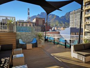 uma varanda com cadeiras e um guarda-sol num edifício em Urban Oasis Aparthotel em Cidade do Cabo