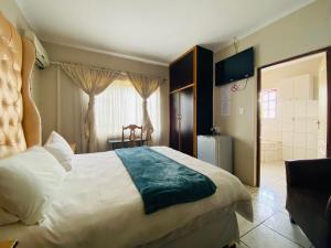 Un dormitorio con una cama grande y un baño. en Sidze Guest House, en Polokwane