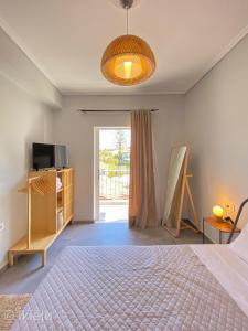 1 dormitorio con 1 cama, TV y ventana en Theros Lux Apts., en Plános