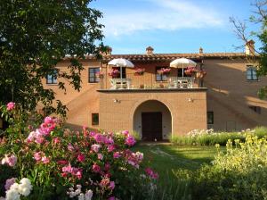 a building with a balcony with flowers in the yard at Agriturismo Il Poderino in Asciano