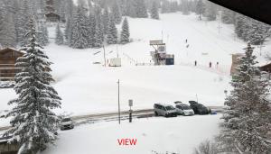 een met sneeuw bedekte skipiste met in de sneeuw geparkeerde auto's bij Ski-in Apartment in Anzere in Anzère
