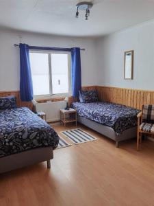 1 dormitorio con 2 camas y ventana en Arctic Colors Northern Lights Apartments en Porjus