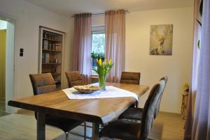 een eettafel met stoelen en een vaas met bloemen bij Haus Waldesruh in Lennestadt