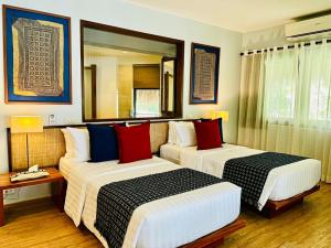 a hotel room with two beds and a mirror at Amun Ini Beach Resort & Spa in Anda