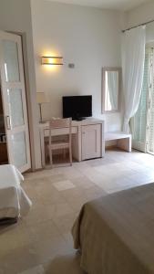 a bedroom with a bed and a tv and a chair at Hotel Alta La Vista in Marina di Castagneto Carducci