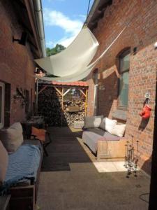 un patio con sofá y toldo en un edificio de ladrillo en Charmante Dorfschule, en Hohenhameln