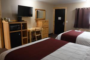 a hotel room with two beds and a desk with a television at Woodside Dells Hotel & Suites in Wisconsin Dells